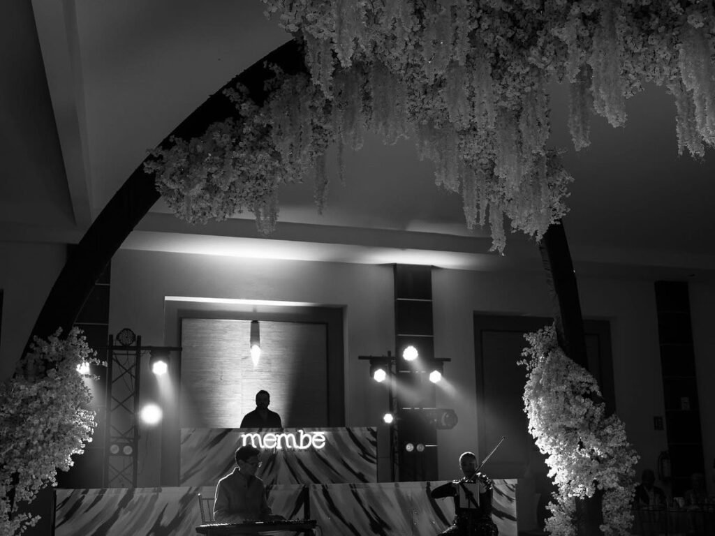 Salón de eventos decorado con un arco de flores blancas, iluminación y música en vivo en una fiesta organizada por membē en Zacatecas
